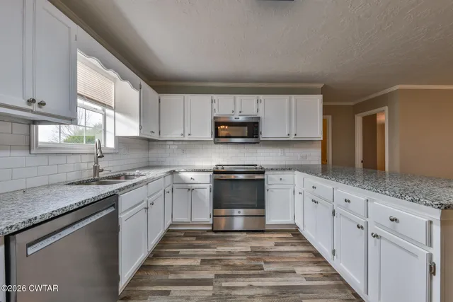 a kitchen with granite countertop a sink and a stove top oven
