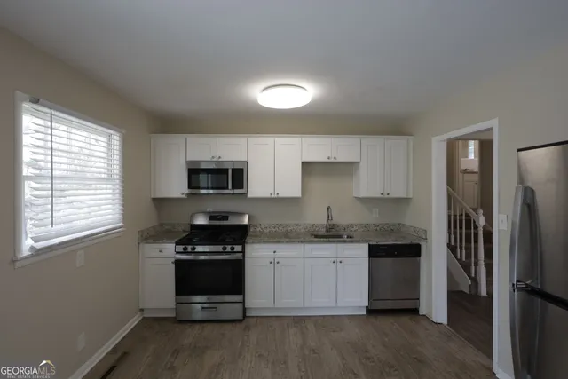 a kitchen with stainless steel appliances a stove a sink a refrigerator and a microwave