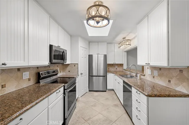 a kitchen with granite countertop stainless steel appliances a sink cabinets and a window