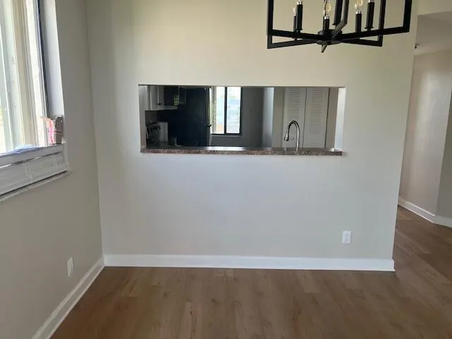a view of a hallway with wooden floor and chandelier