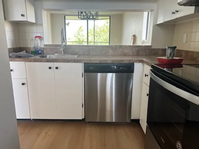 a kitchen with granite countertop a sink cabinets and stainless steel appliances