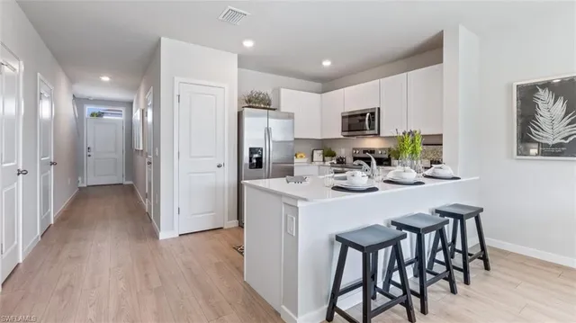 a kitchen with stainless steel appliances a dining table chairs and refrigerator