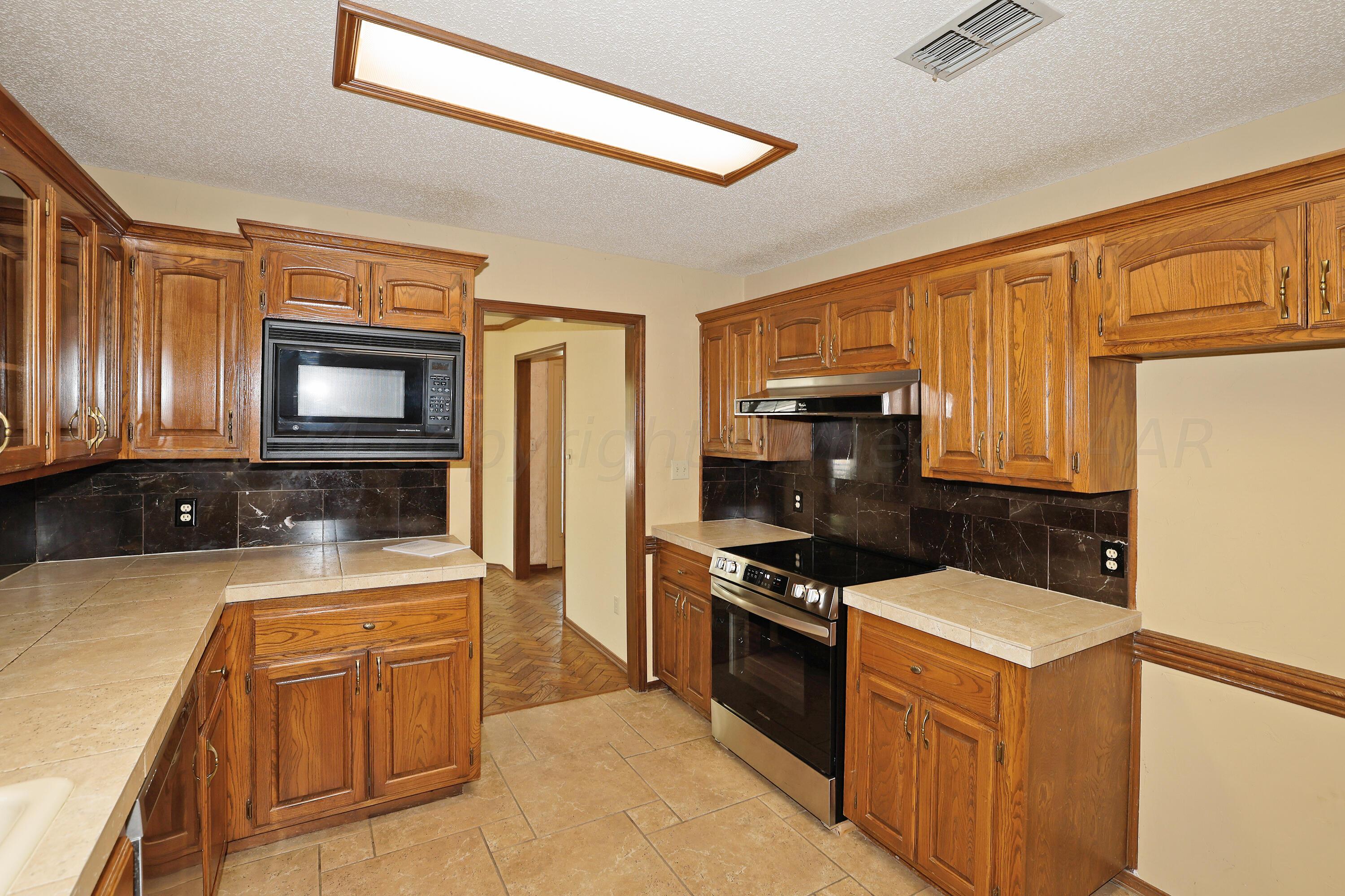 6819 Cloud Crest Drive Amarillo, TX 79124 - Photo 15 of 37 a kitchen with wooden cabinets and a stove top oven