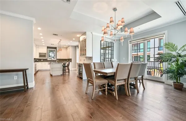 a dining room with wooden floor a chandelier a wooden table and chairs