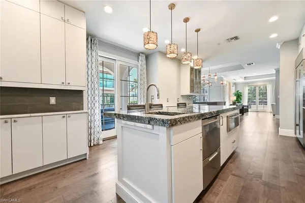 a kitchen with kitchen island granite countertop a sink cabinets and stainless steel appliances