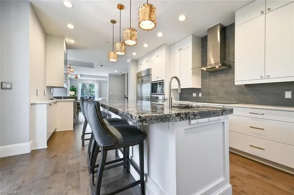 a kitchen with stainless steel appliances kitchen island granite countertop a table chairs sink and cabinets