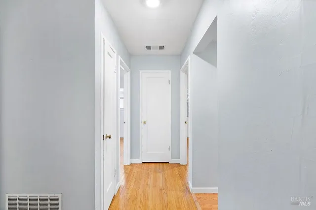 a view of a hallway with wooden floor and a bathroom