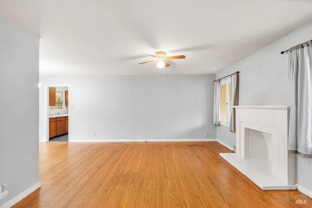 a view of empty room with wooden floor and fireplace