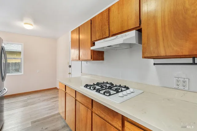 a kitchen with a sink a stove cabinets and wooden floor