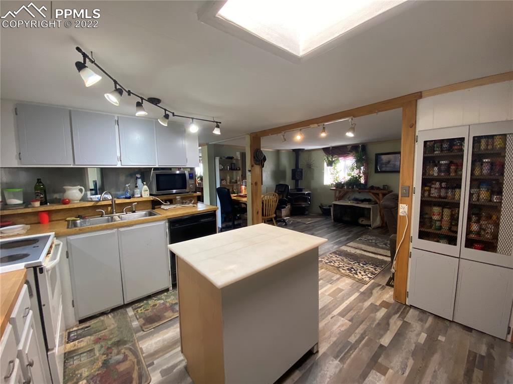 33895 East Jones Road Yoder, CO 80864 - Photo 16 of 45 a kitchen with stainless steel appliances kitchen island granite countertop a refrigerator a stove and a sink with wooden floor