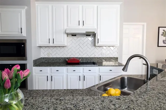 a kitchen with stainless steel appliances granite countertop a sink a stove and white cabinets