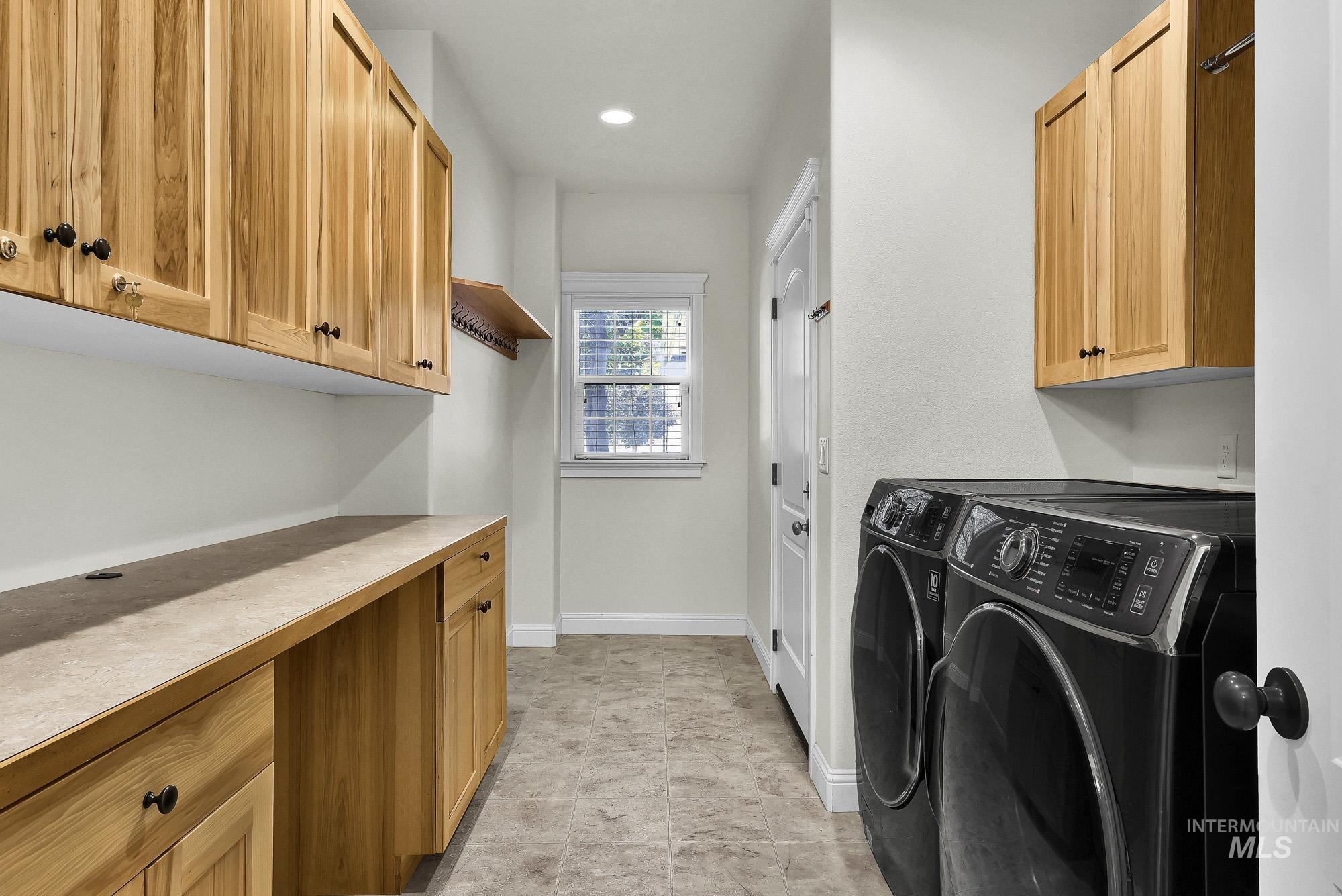 2172 West Cedar Grove Street Meridian, ID 83646 - Photo 20 of 49 Laundry room featuring light wood-finish cabinetry with dark hardware, a spacious countertop, and a window providing natural light