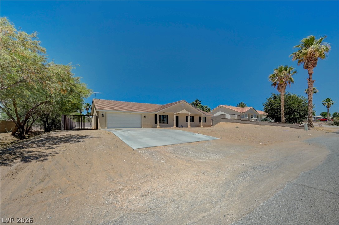 1272 Liston Avenue Logandale, NV 89021 - Photo 4 of 61 A desert oasis with a paved driveway and mature palm trees offers secluded living under a brilliant sky.