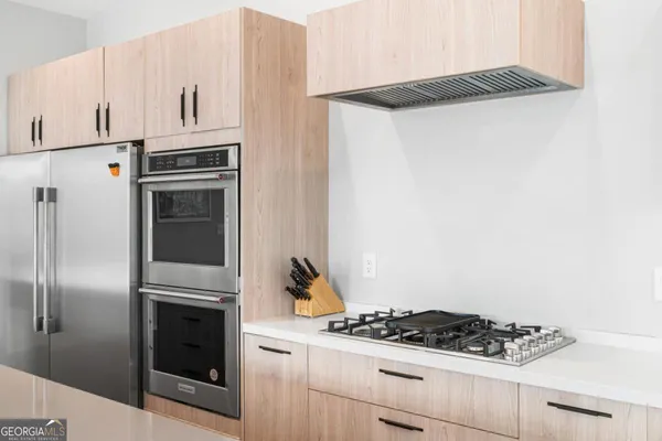 a kitchen with stainless steel appliances a white table chairs and wooden floors