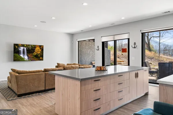 a kitchen with stainless steel appliances granite countertop a stove a sink a refrigerator and white cabinets with wooden floor