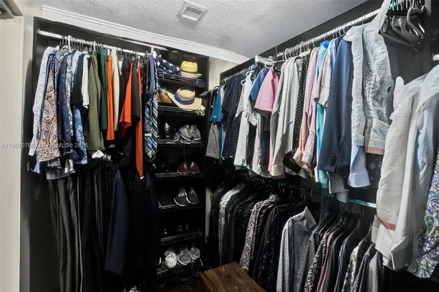 a view of walk in closet with clothes and shoes