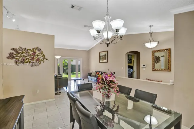 a dining room with wooden floor a chandelier a wooden table and chairs