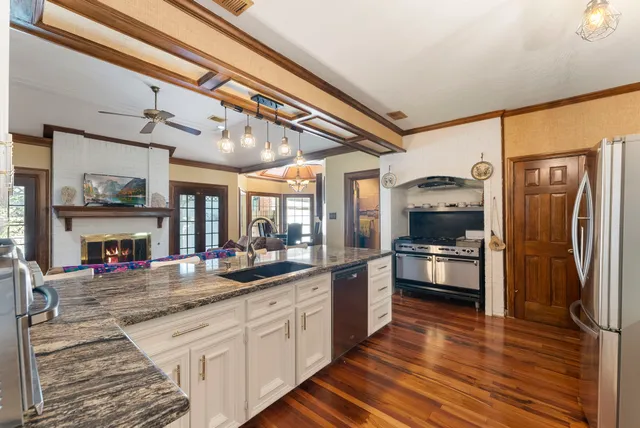 a kitchen with stainless steel appliances a refrigerator a sink and wooden floors