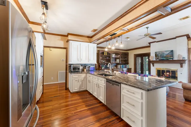 a view of a dining room and livingroom with furniture wooden floor a chandelier