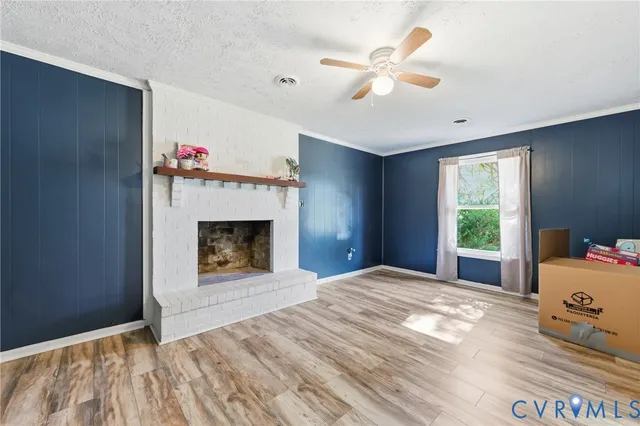 a view of empty room with wooden floor and fireplace