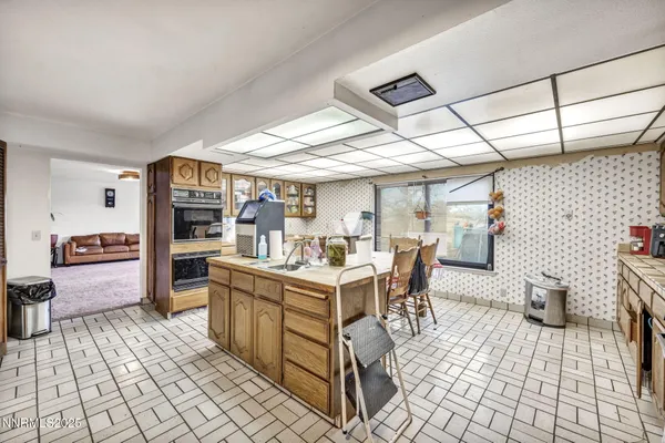 a kitchen with stainless steel appliances granite countertop a sink a stove a dining table and chairs with wooden floor