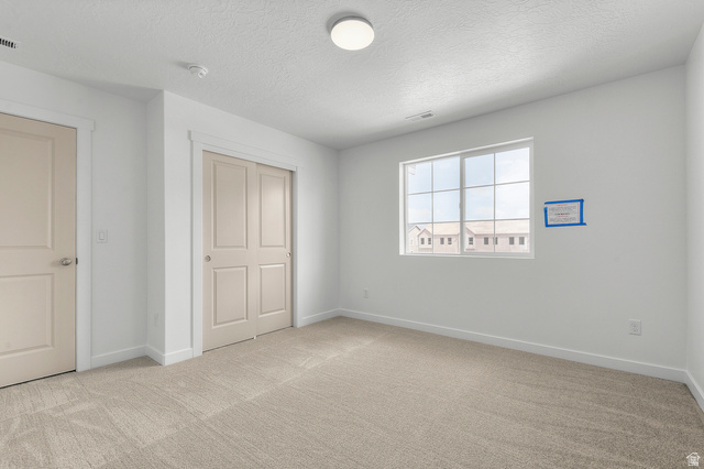 7797 West Alta Springs Way Magna, UT 84044 - Photo 19 of 21 Unfurnished bedroom featuring light colored carpet, a closet, and a textured ceiling