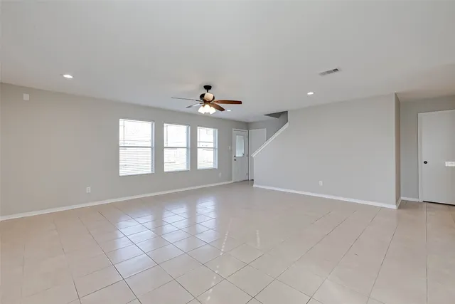an empty room with windows and ceiling fan