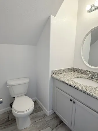 a bathroom with a granite countertop toilet and a sink