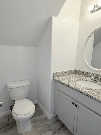 a bathroom with a granite countertop toilet and a sink