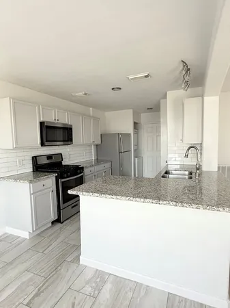 a kitchen with stainless steel appliances granite countertop a sink a stove top oven a granite counter space and cabinets