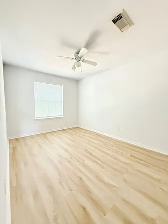 an empty room with a windows and ceiling fan