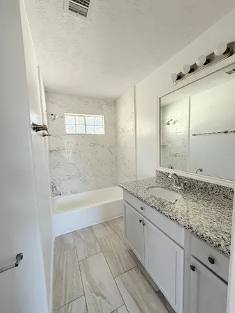 a bathroom with a granite countertop sink a toilet and bathtub