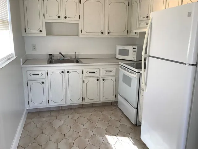 a kitchen with white cabinets and white appliances