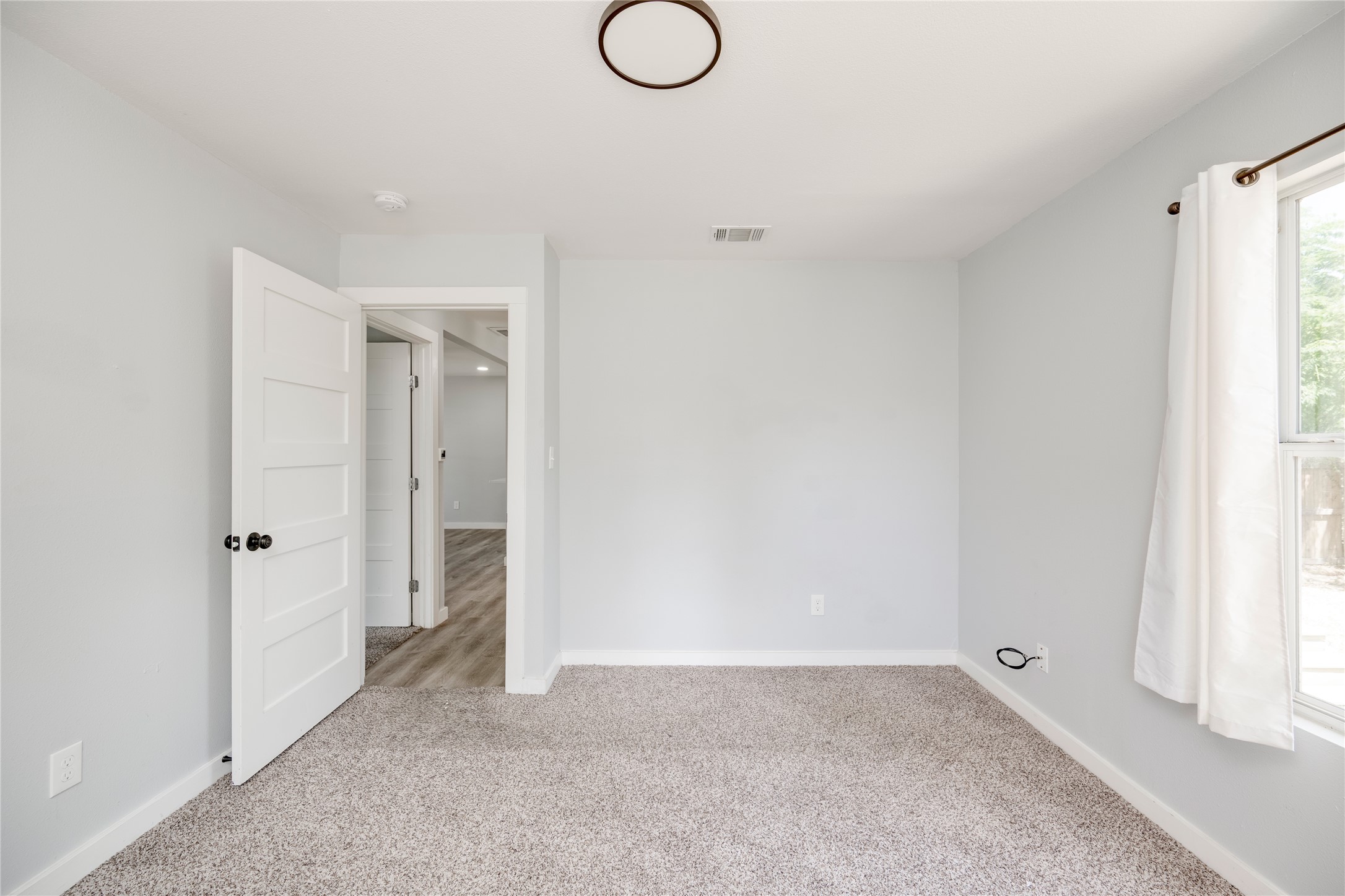 1400 Marcus Place, Unit B Austin, TX 78721 - Photo 11 of 39 A well-lit bedroom features plush carpeting and a modern light fixture, offering a comfortable personal retreat.