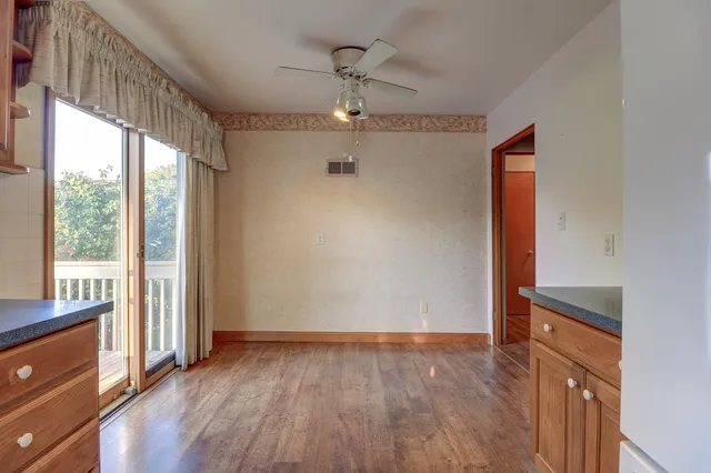 an empty room with wooden floor fan and windows