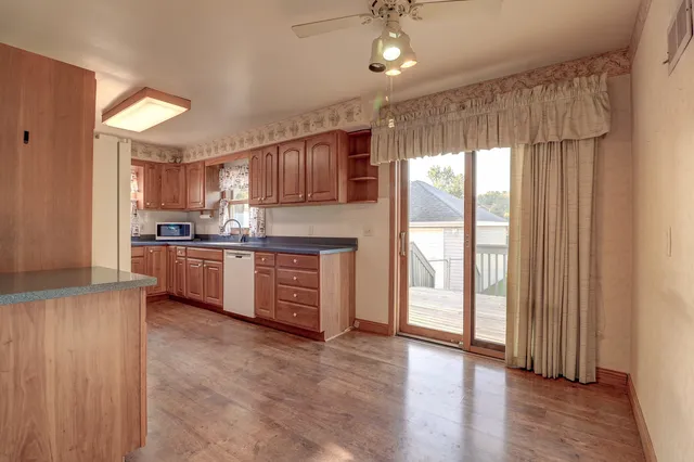 a kitchen with stainless steel appliances granite countertop a refrigerator a sink dishwasher a stove and white countertops with wooden floor