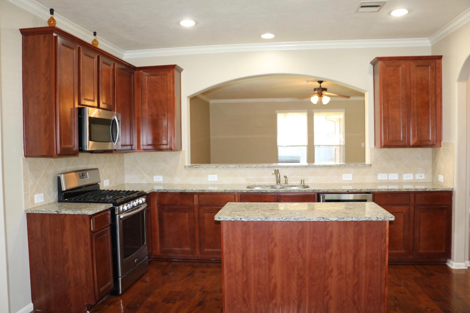 17618 Bryce Manor Lane Humble, TX 77346 - Photo 9 of 14 a kitchen with kitchen island granite countertop wooden cabinets stainless steel appliances a sink and a window