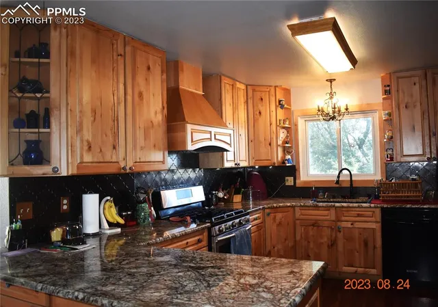 a kitchen with stainless steel appliances granite countertop a refrigerator a stove and a sink with wooden cabinets