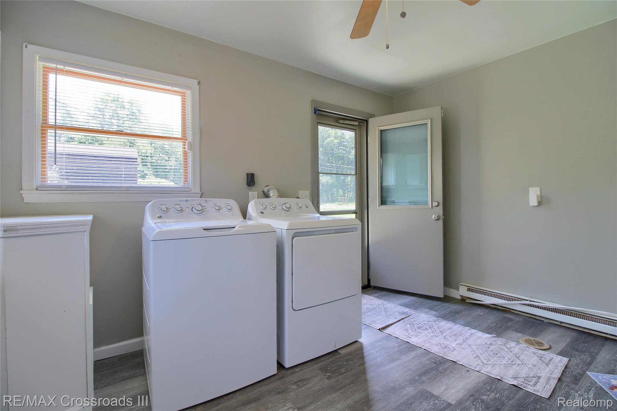 41509 Riggs Road Belleville, MI 48111 - Photo 13 of 26 Dedicated laundry area featuring modern appliances, a large window with blinds, wood-finish flooring, a ceiling fan, and direct exterior access