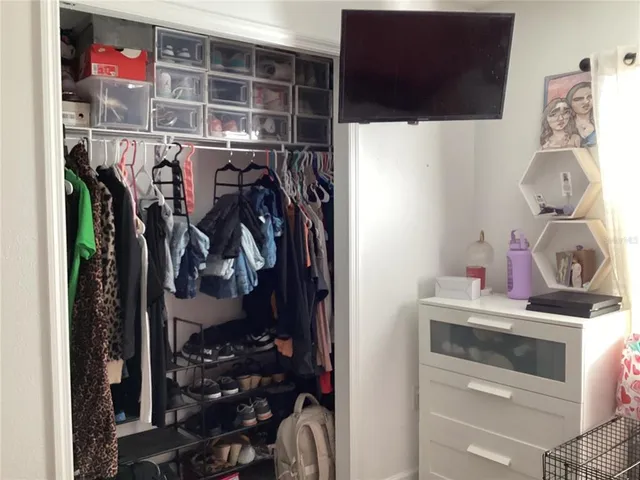a view of walk in closet with clothes and shoes