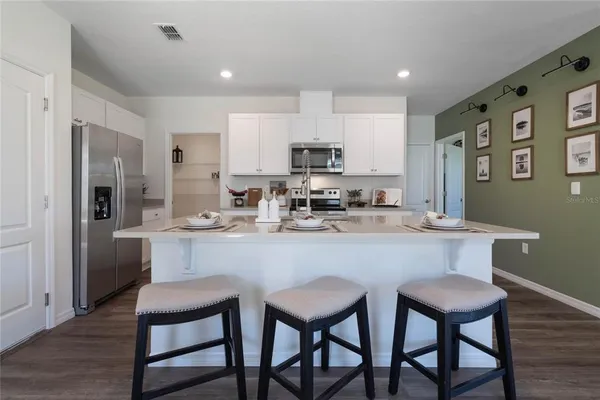 a kitchen with stainless steel appliances granite countertop a dining table chairs refrigerator and cabinets