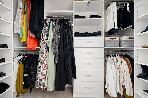 a view of walk in closet with clothes and shoes
