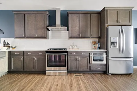 a kitchen with granite countertop a refrigerator stove and wooden floor