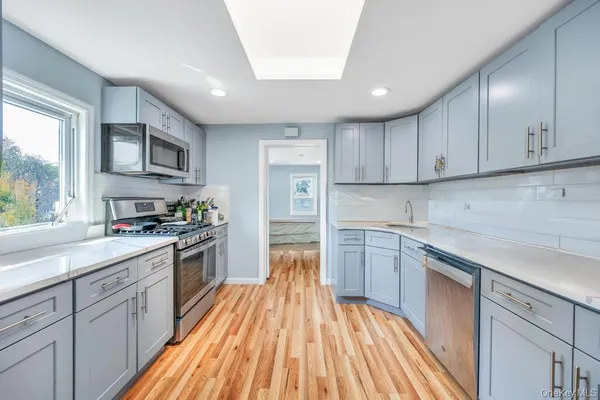 a kitchen with cabinets wooden floor and stainless steel appliances