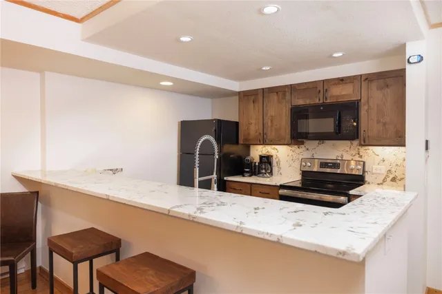 a kitchen with stainless steel appliances a sink a stove a microwave a refrigerator a counter top space and cabinets