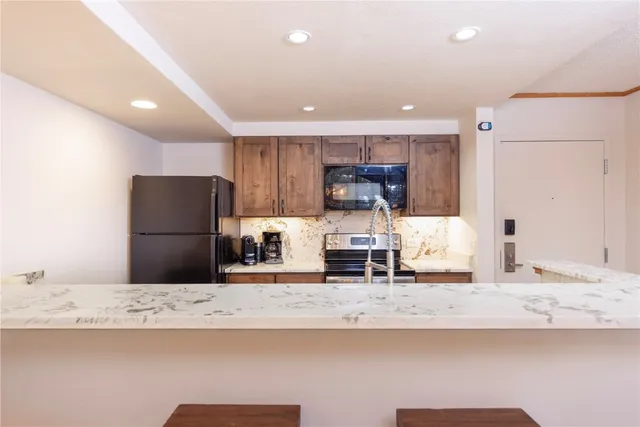 a kitchen with stainless steel appliances granite countertop a sink a stove a refrigerator and a refrigerator