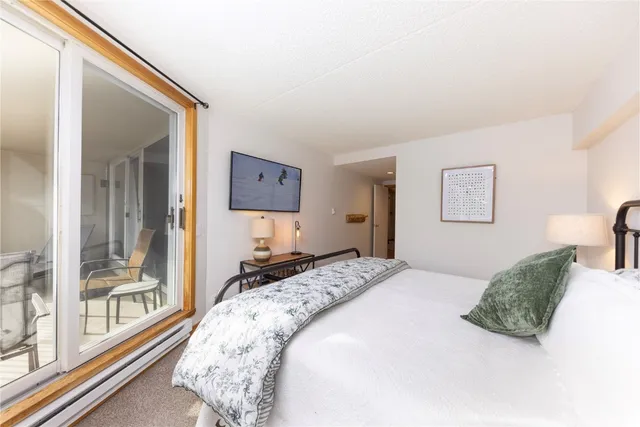 a bedroom with a bed and a large mirror next to a window