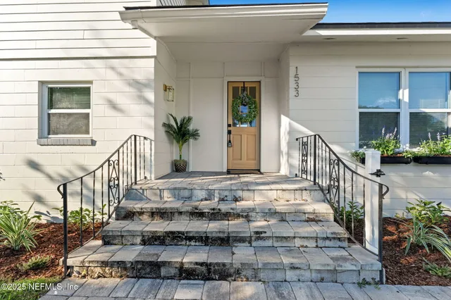 a living room with furniture a potted plant and open kitchen view