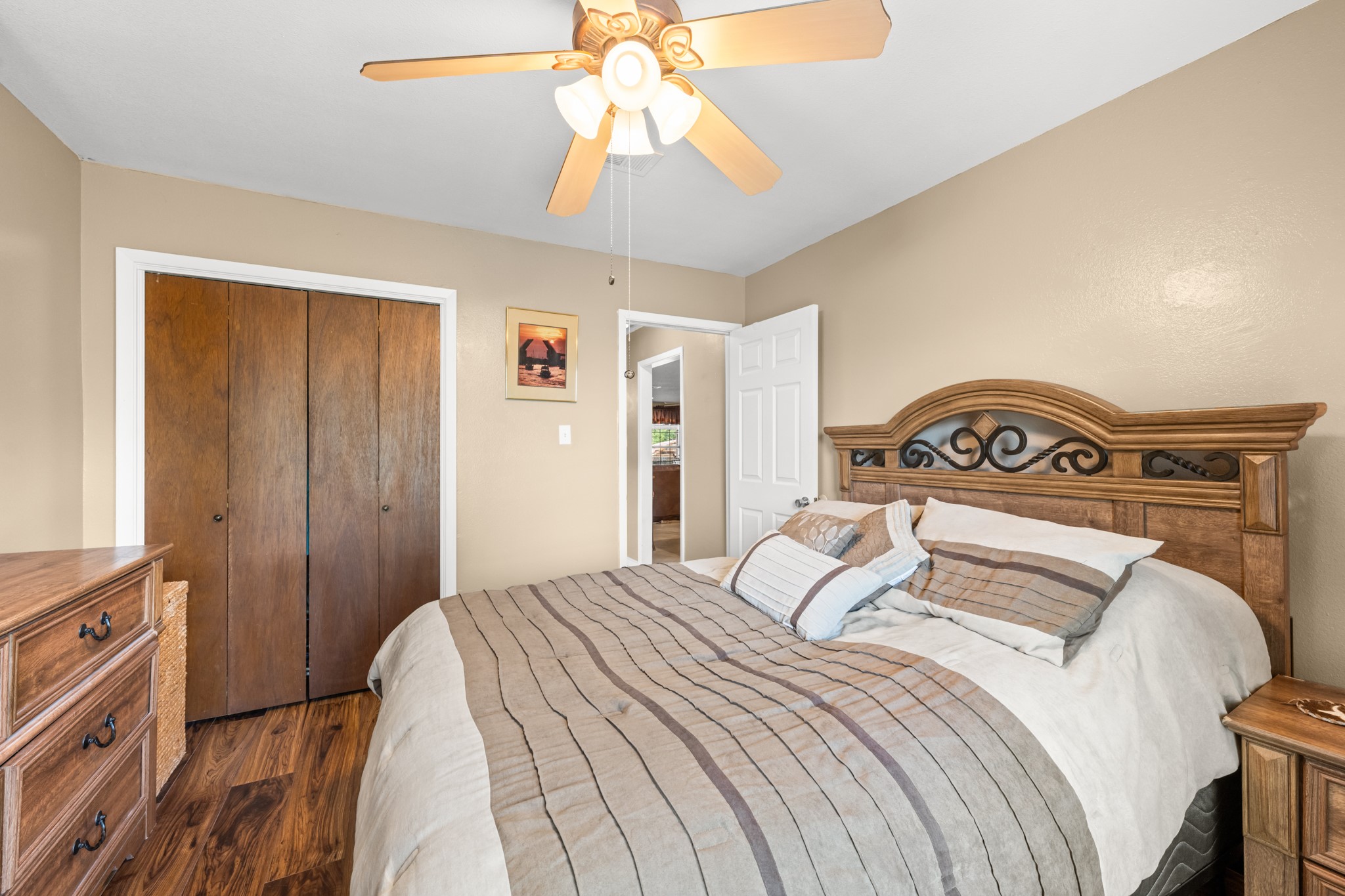 15602 Fir Road Santa Fe, TX 77517 - Photo 22 of 42 Spacious bedroom with rich wood-look flooring, neutral color palette, and ample closet storage. The ceiling fan and well-designed layout provide a comfortable and relaxing space to unwind.