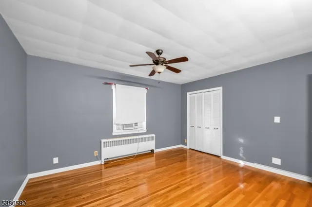 a view of empty room with wooden floor and ceiling fan